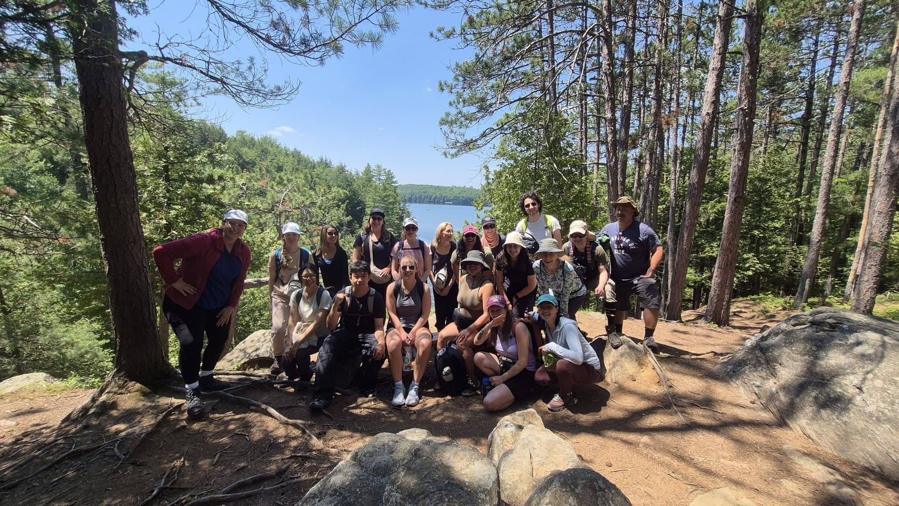 A Parkbus group spread across a rock lookout in Algonquin, looking out over forest and lakes