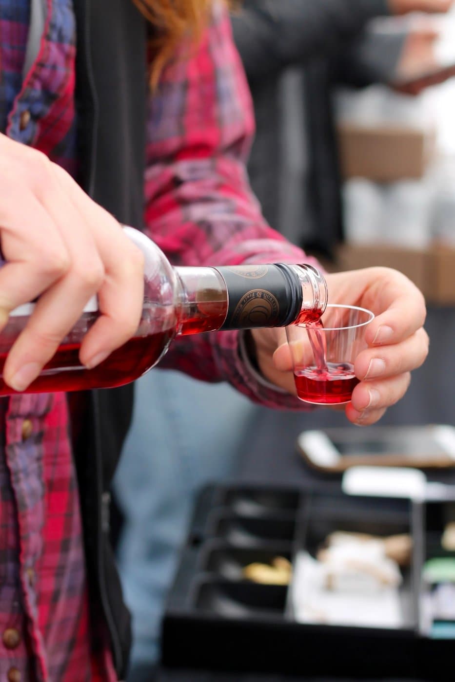 Cranberry wine being poured from a bottle into a small tasting cup at the winery