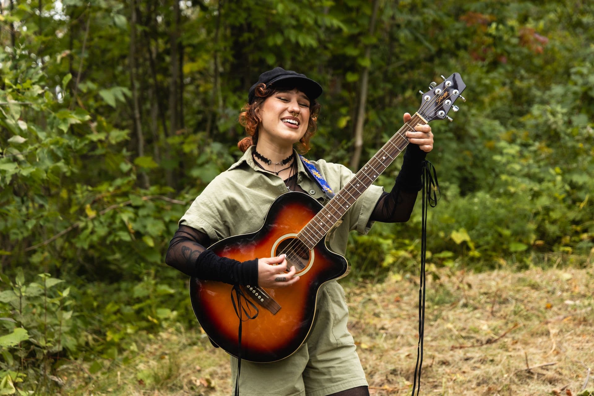 A musician playing an acoustic guitar in the woods along the Guitar Trail