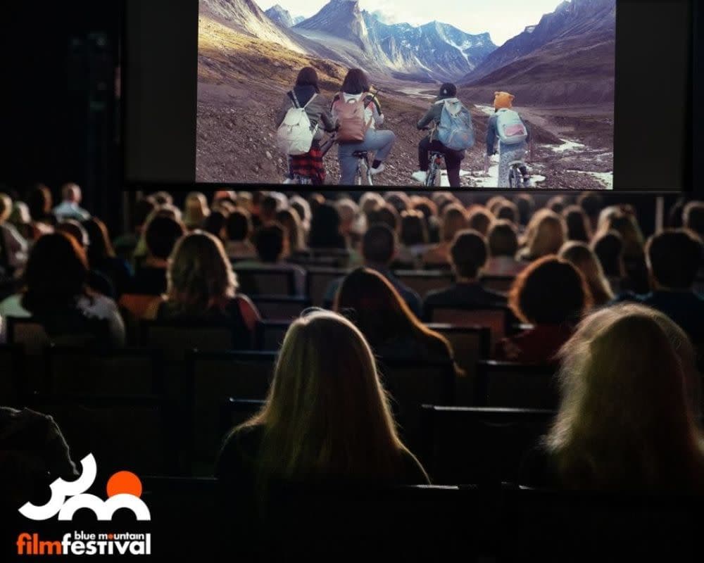 A full auditorium watching a mountain landscape on screen at the film festival