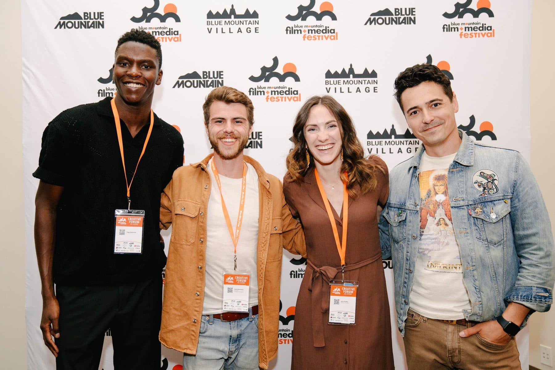 Four festival guests standing together in front of the festival's branded backdrop