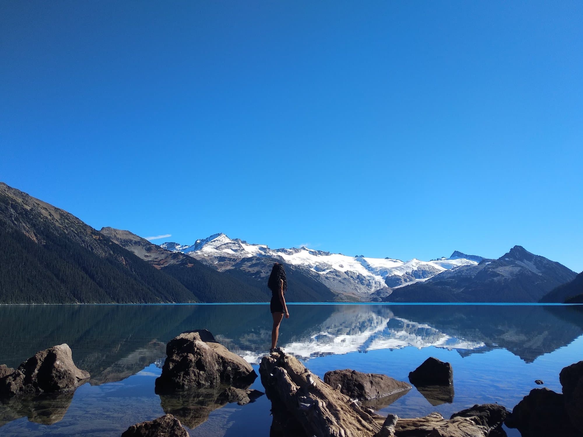 One walker on the rocks above Garibaldi Lake, with the glacier behind