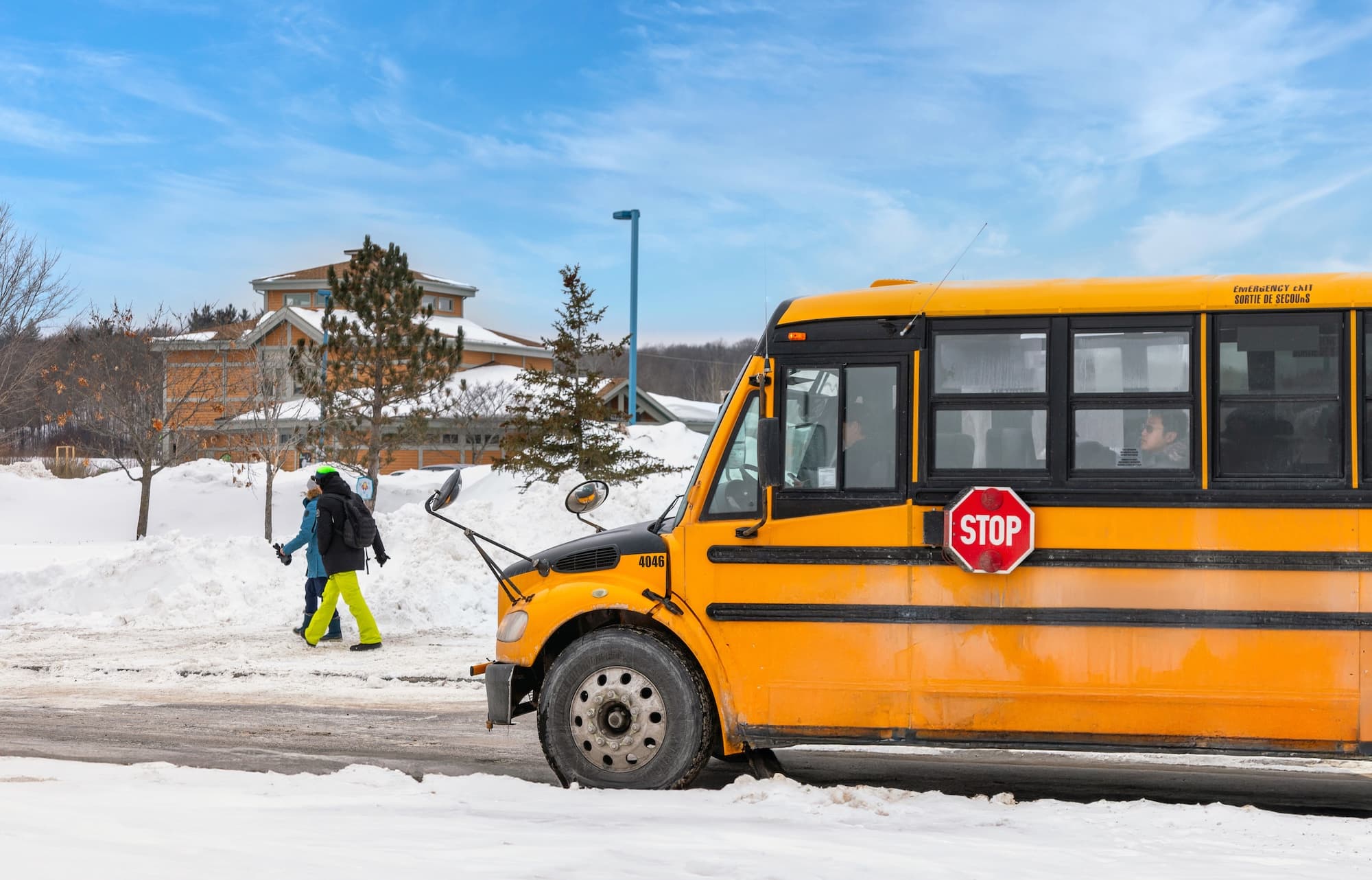 A yellow shuttle bus parked in the snow outside the lodge in Gatineau Park