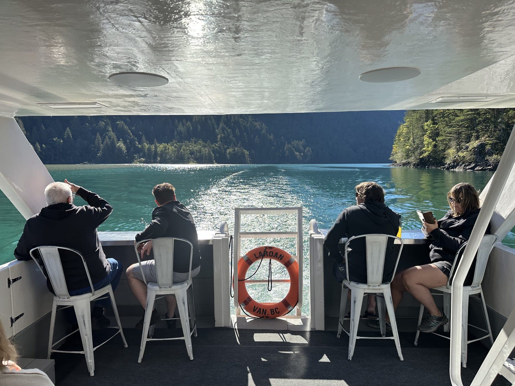 The open deck of the Shoreline Tours boat, with the wake and the far shore behind
