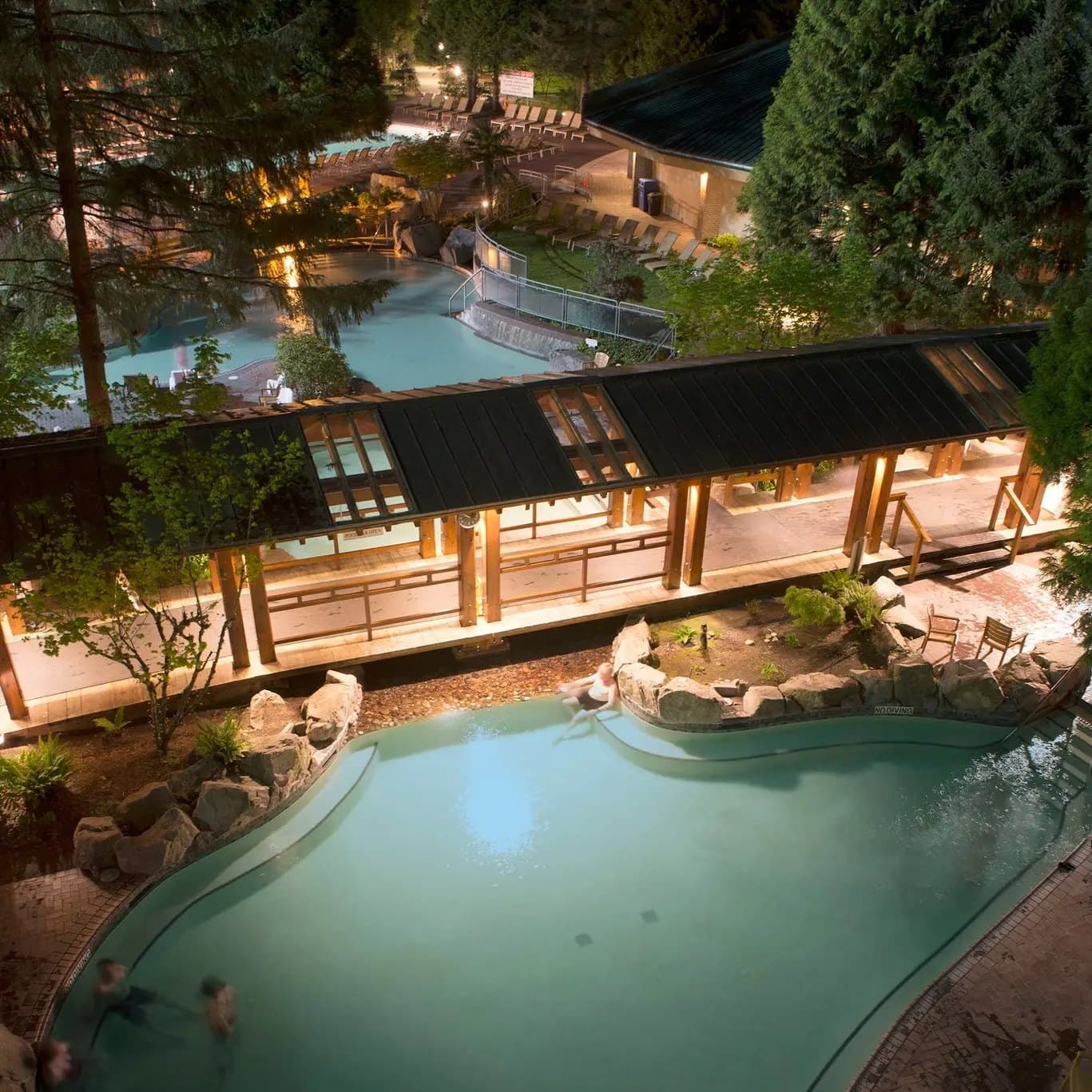 The hot spring pools at Harrison Hot Springs Resort, lit up among the trees in the evening