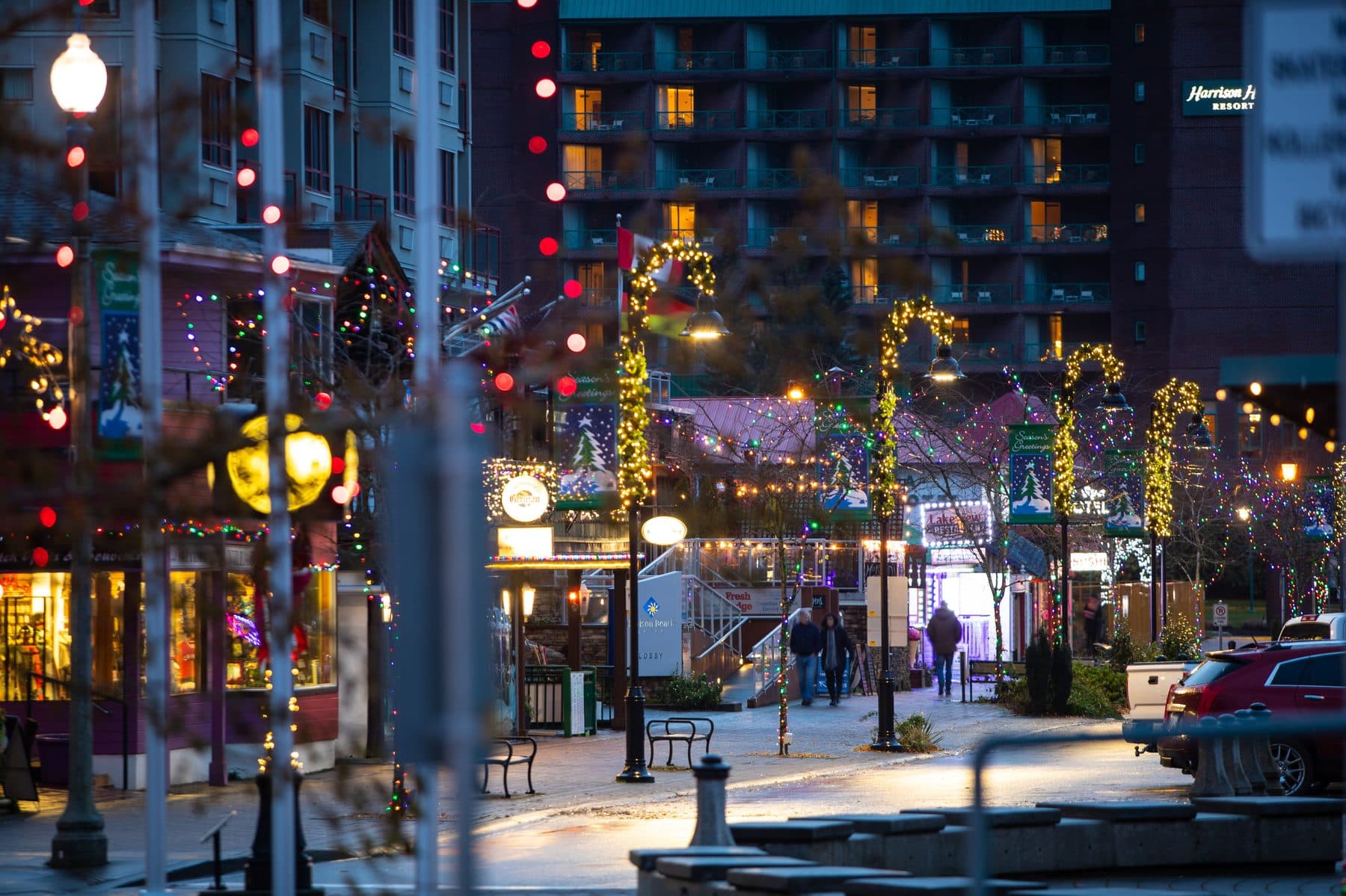 The main street of Harrison Hot Springs, shops lit up along the lakefront