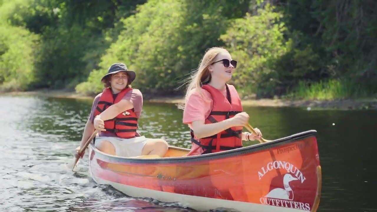 Two friends paddling an Algonquin Outfitters canoe