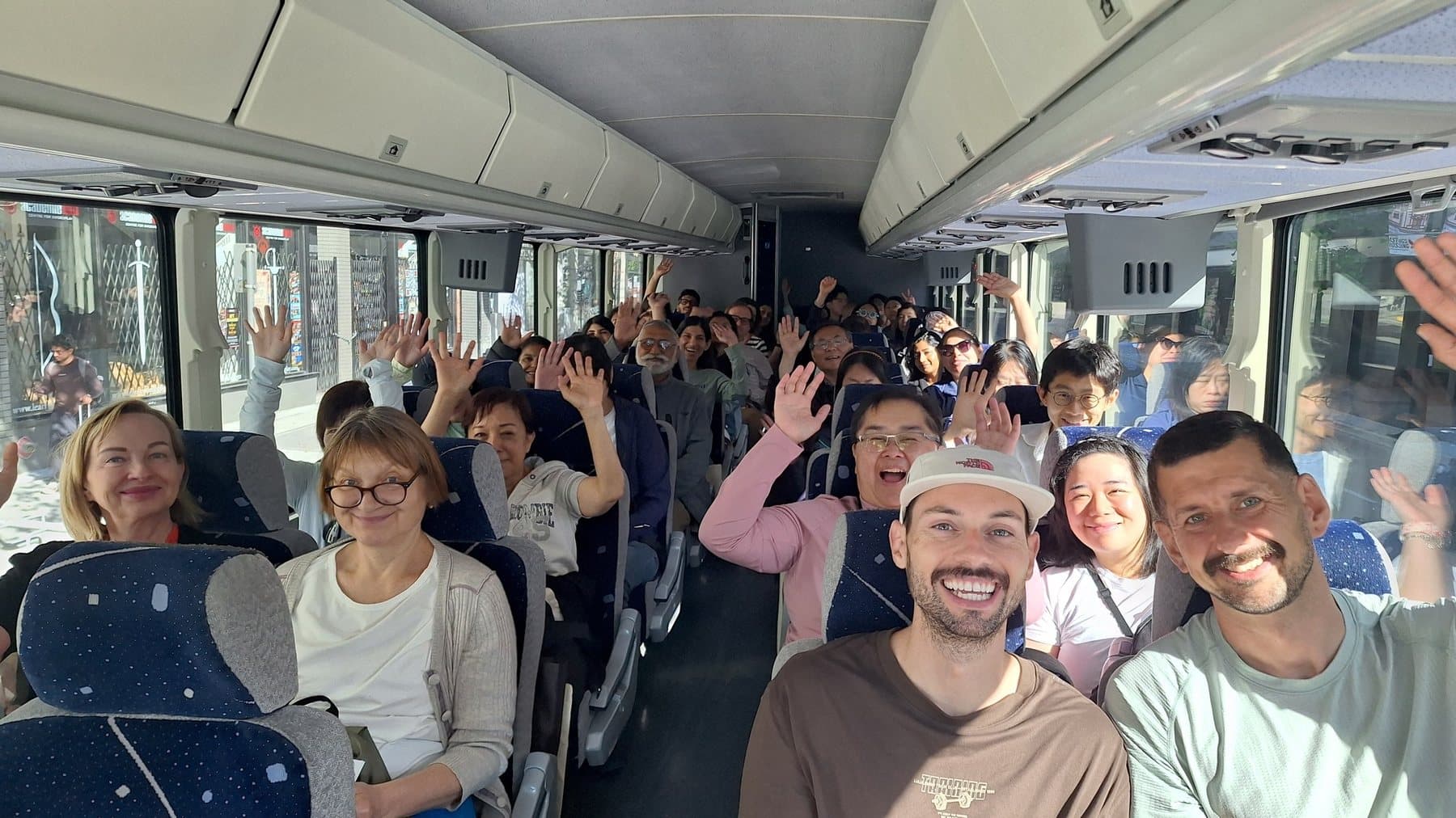 A coach full of Parkbus passengers waving, on the way to the park