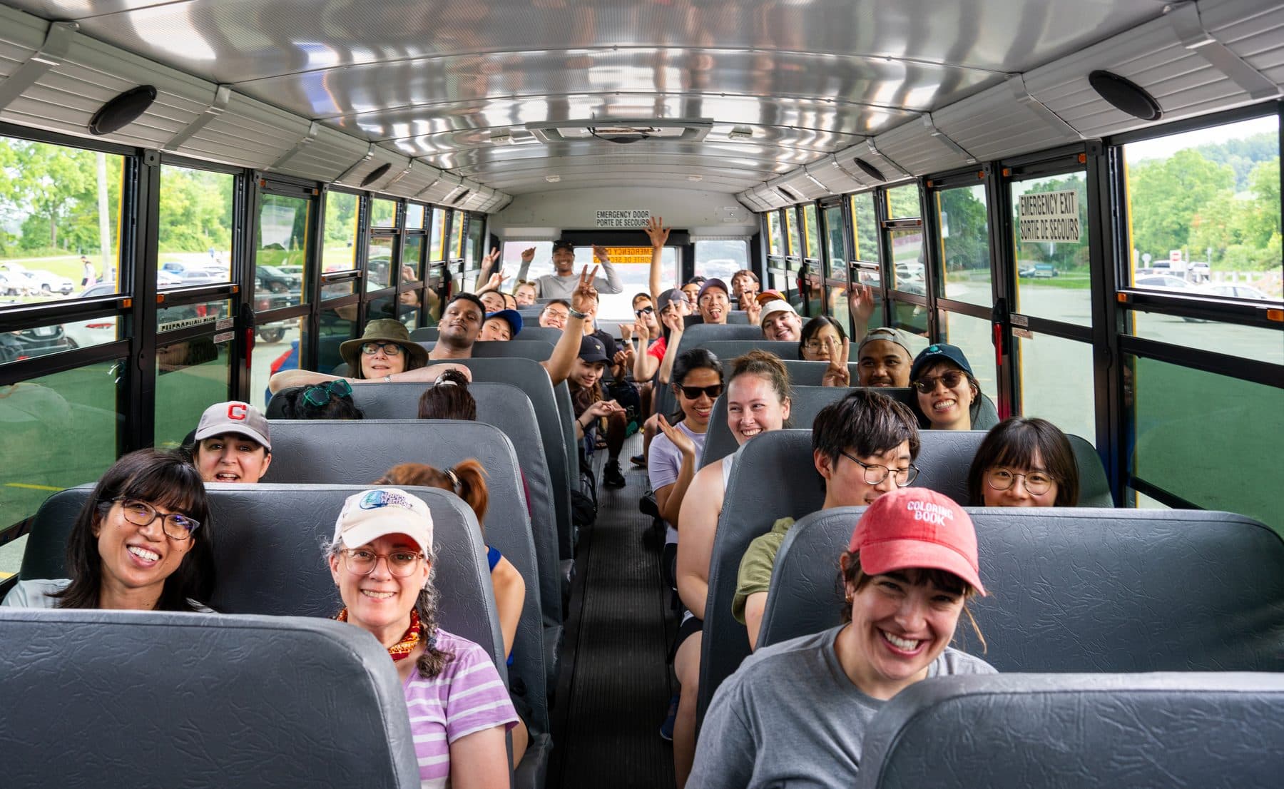 A yellow school bus full of Parkbus passengers, parked at the trailhead with the windows down