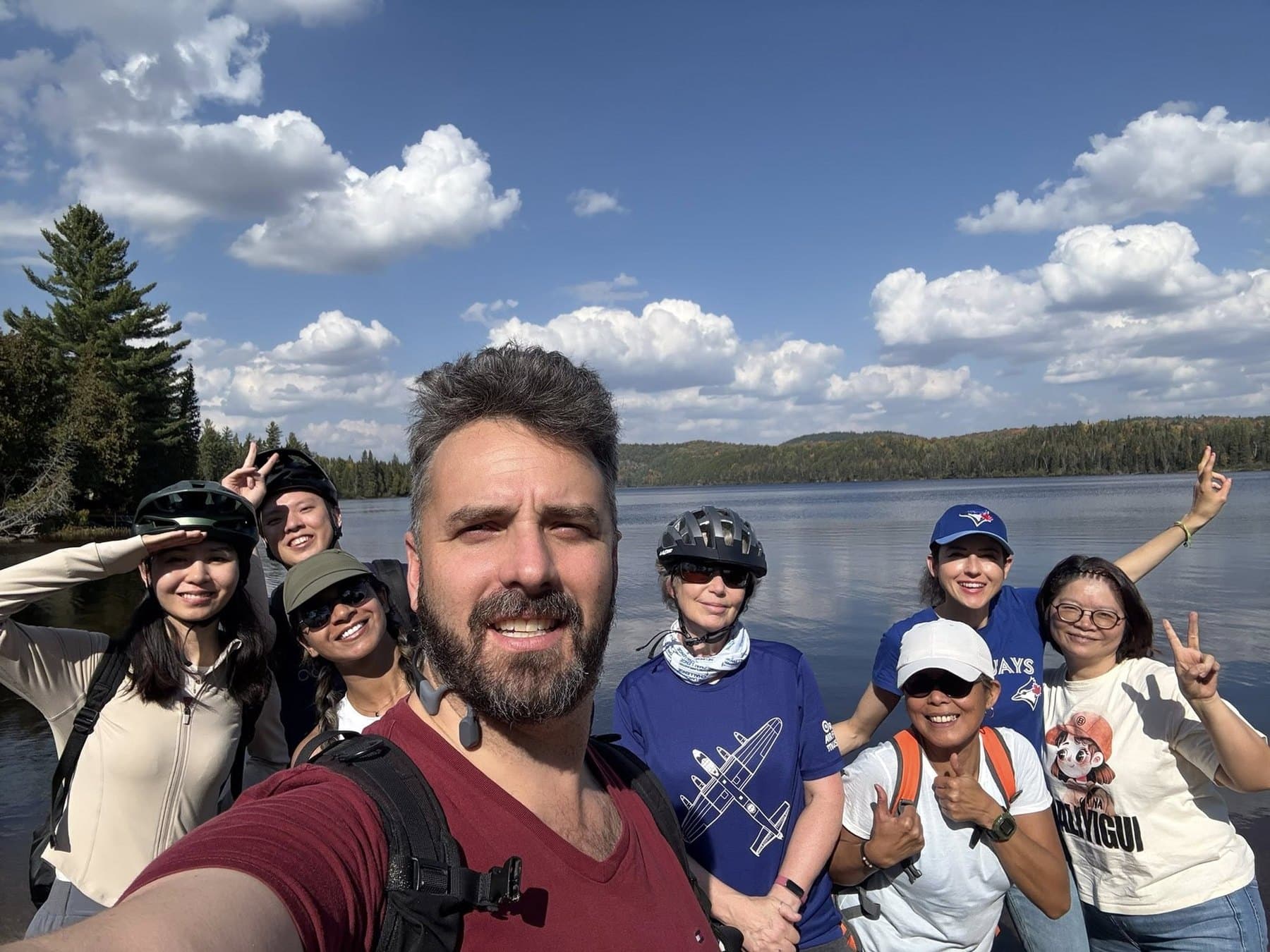 A Parkbus group in bike helmets gathered at the edge of a lake on a guided cycling day