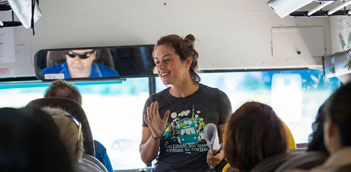 A Parkbus guide at the front of the coach talking to passengers
