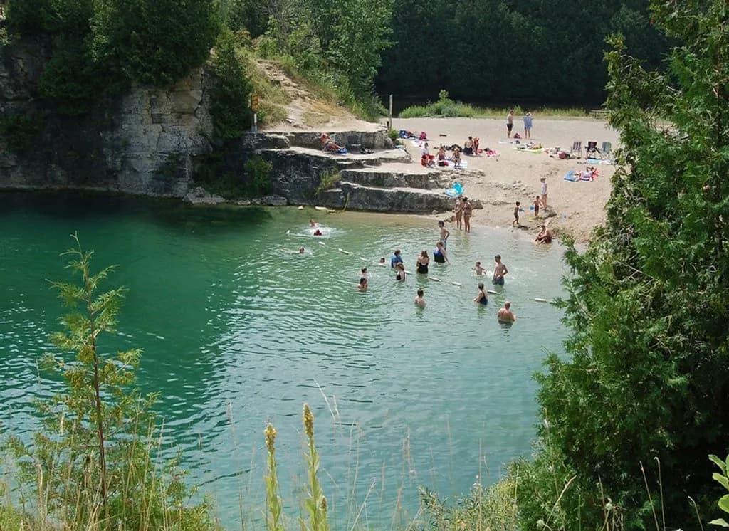Swimmers in the shallow end of Elora Quarry with the limestone cliff behind