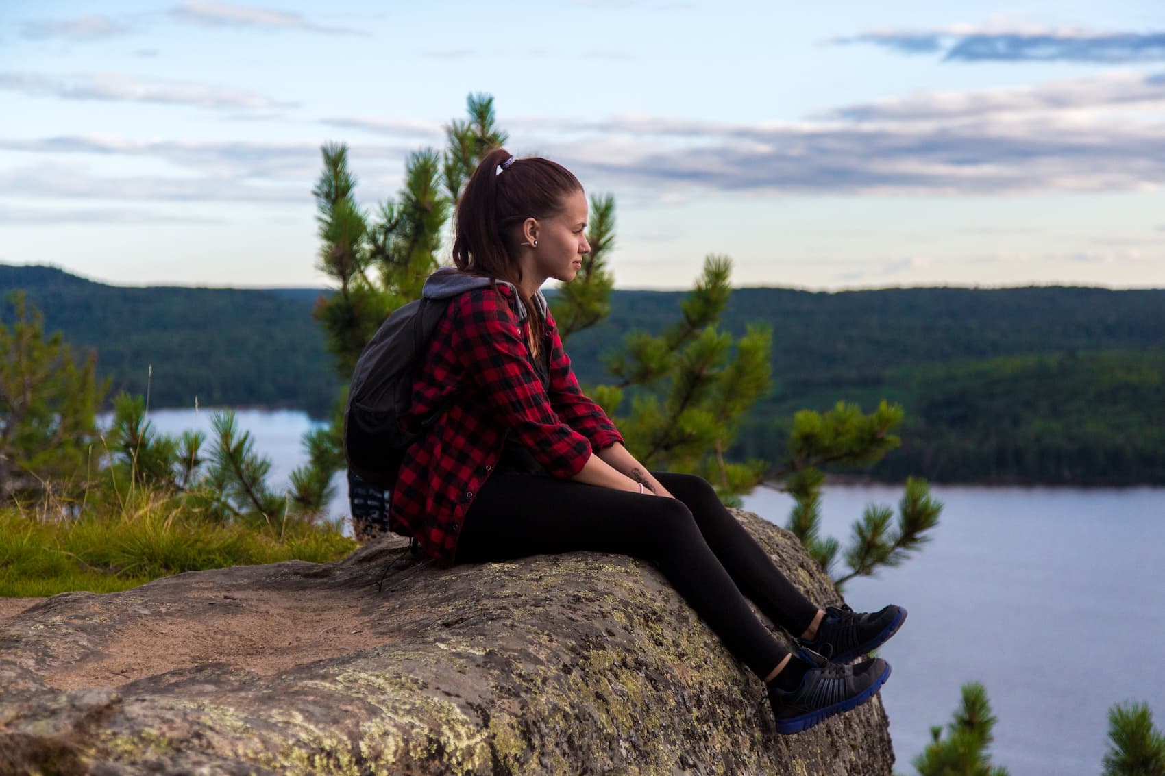 A rider sitting on a rock above a lake in Algonquin, taking a break