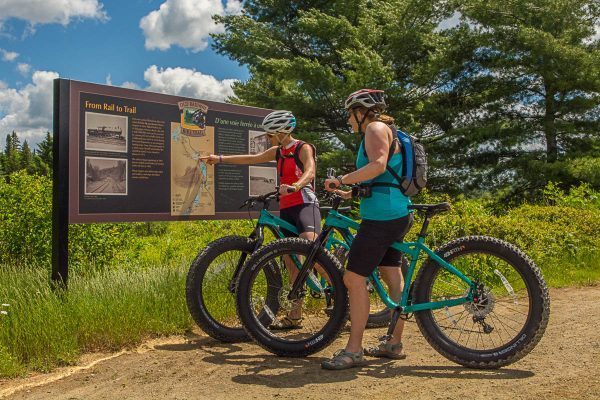 Two riders stopped at a trail sign on Algonquin's Old Rail Trail