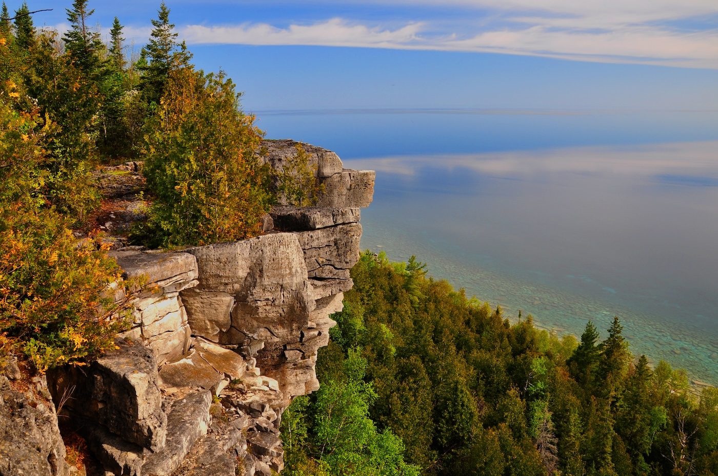 A limestone cliff above the water, with autumn forest along the shore below
