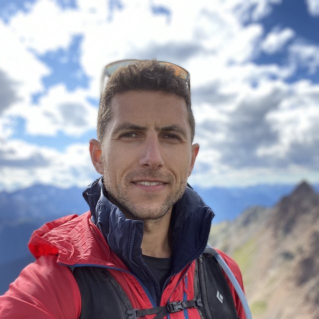 Alex Z. Berlyand on a mountain ridge in a red jacket